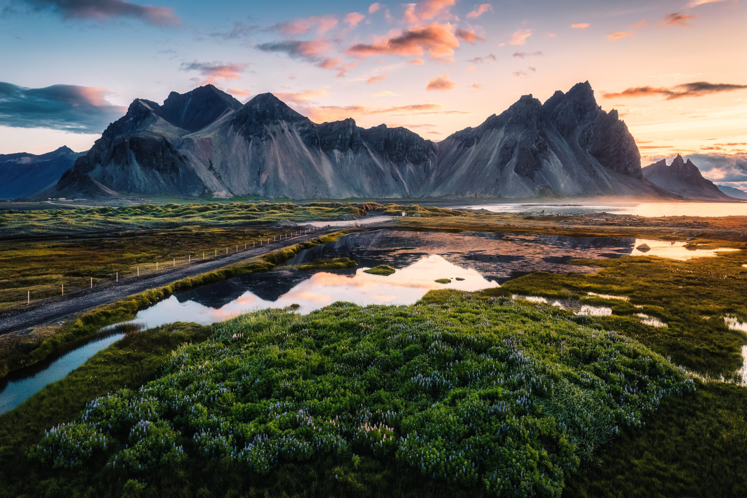 Montagne e vegetazione si riflettono nell’acqua nella luce del tramonto