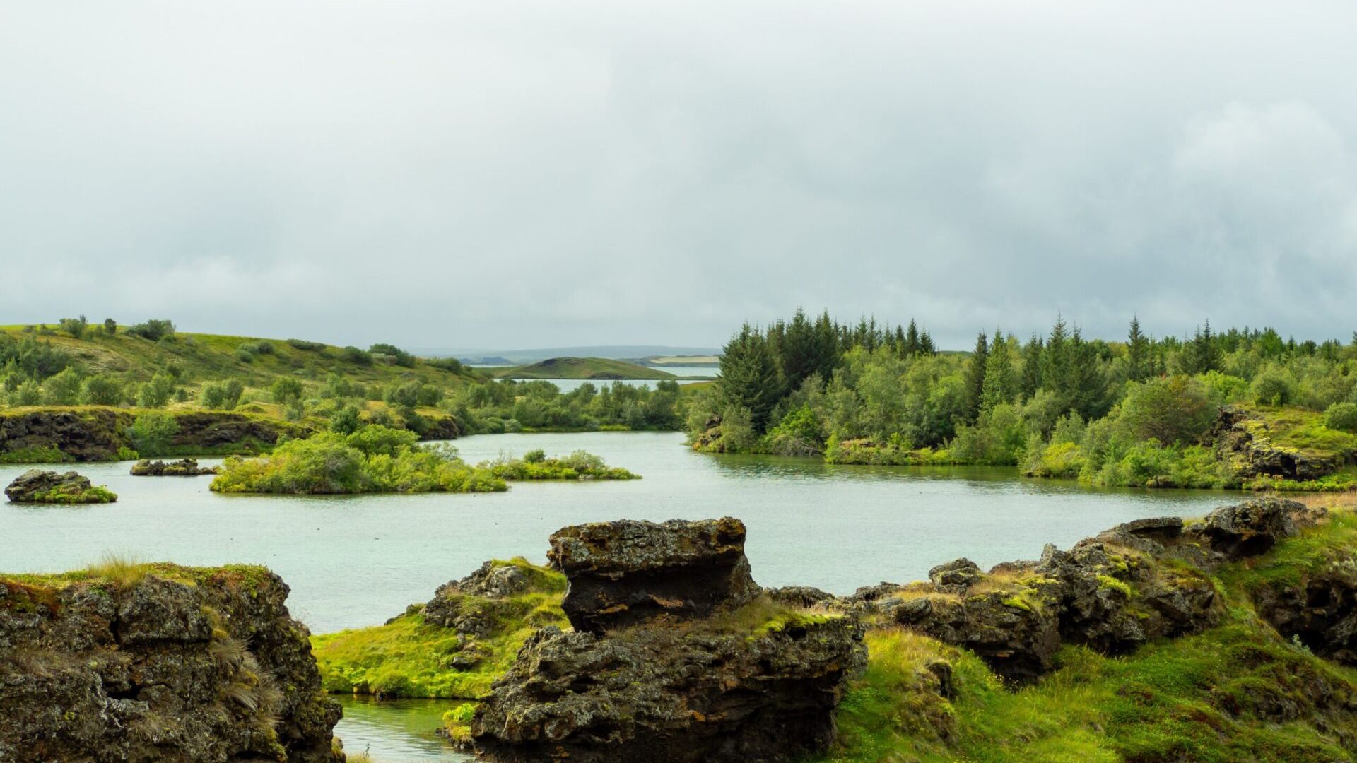 Specchio d’acqua circondato da rocce laviche, vegetazione e alberi
