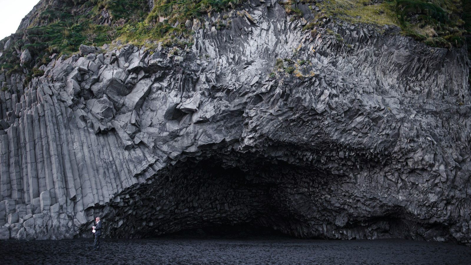 Grotta e colonne di basalto sulla spiaggia nera della costa meridionale islandese